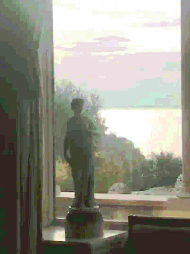 A window seat beneath columns, overlooking calm water at dusk.